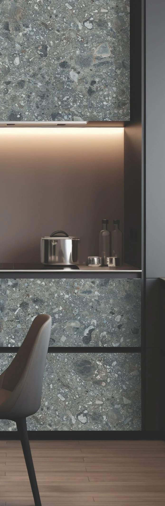 Modern kitchen with grey terrazzo surfaces, under-cabinet lighting, and a stainless steel pot.
